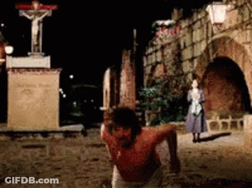 A Statue Of Jesus On A Cross Is In The Background GIF