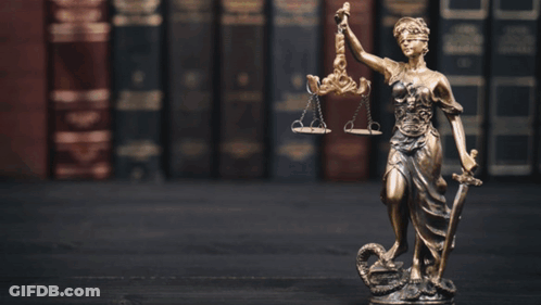 A Statue Of Lady Justice Holding Scales Of Justice And A Sword GIF