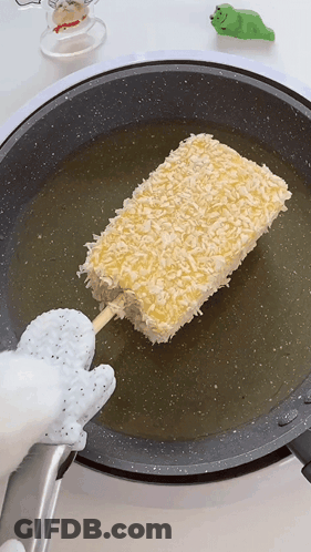 A Stick Of Food Is Being Cooked In A Pan GIF