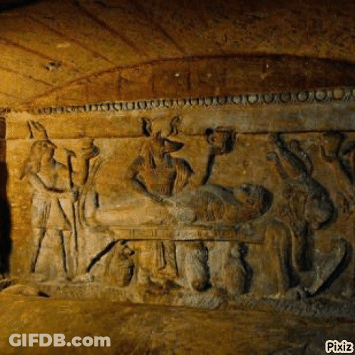 A Stone Carving Of A Man Laying On A Bed In A Cave Surrounded By Animals . GIF