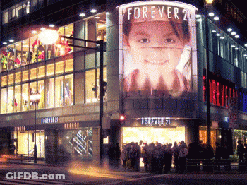 A Store Front With A Large Billboard That Says Forever 21 On It GIF