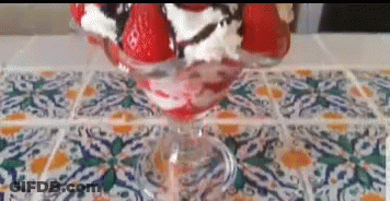A Strawberry Sundae With Whipped Cream And Chocolate Sauce In A Glass On A Table . GIF