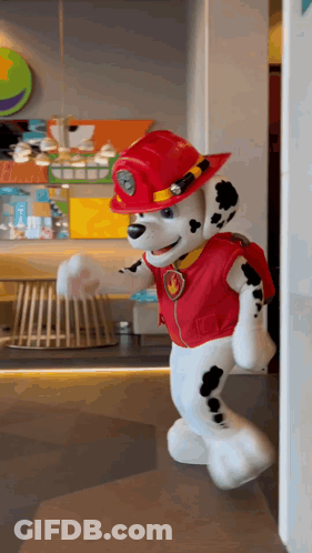 A Stuffed Animal Dressed As Marshall From Paw Patrol Is Walking Through A Doorway GIF