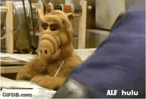 A Stuffed Animal From The Show Alf Is Sitting At A Desk Talking On A Cell Phone GIF