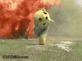 A Stuffed Animal Is Standing In The Grass With Smoke Coming Out Of It 'S Mouth . GIF