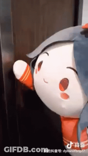 A Stuffed Animal Is Standing Next To A Door And Waving At It . GIF