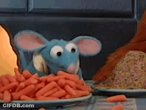 A Stuffed Animal Mouse Is Eating Carrots From A Plate On A Table . GIF