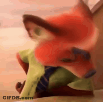 A Stuffed Animal Of A Fox Wearing A Green Shirt And Tie Is Sitting On A Bed . GIF