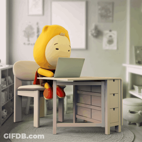 A Stuffed Animal Sitting At A Desk With A Laptop GIF