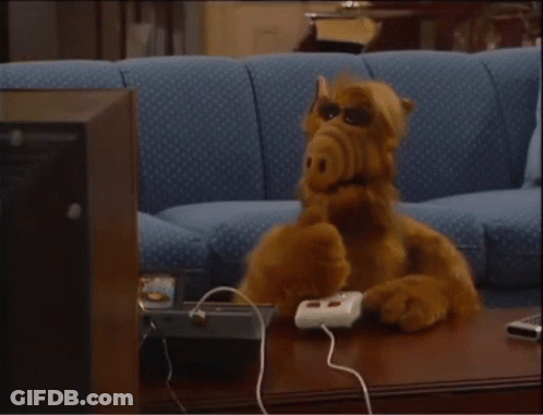 A Stuffed Animal Sitting On A Couch With A Remote Control GIF