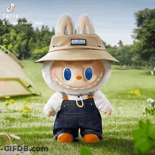 A Stuffed Animal Wearing A Hat And Overalls Is Standing In The Grass With A Tent In The Background GIF