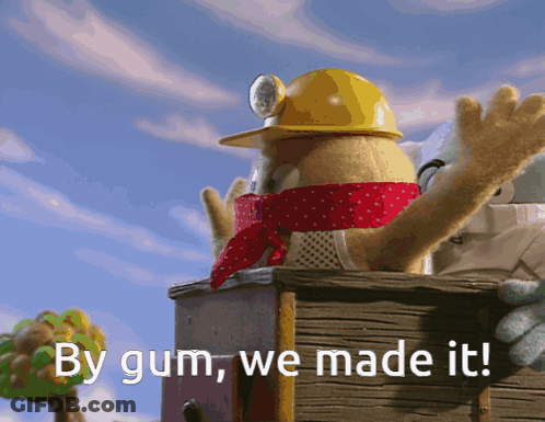 A Stuffed Animal Wearing A Yellow Hard Hat And Scarf Says By Gum We Made It GIF