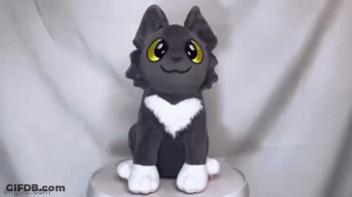 A Stuffed Animal With A Heart On Its Chest Is Sitting On Top Of A Table . GIF