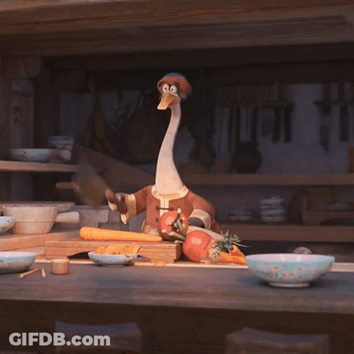A Stuffed Animal With A Long Neck Is Sitting On A Counter With Vegetables GIF
