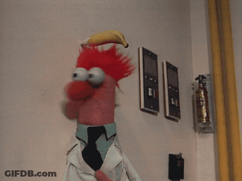 A Stuffed Animal With Bananas In Its Mouth Is Standing In Front Of A Wall With A Fire Extinguisher GIF