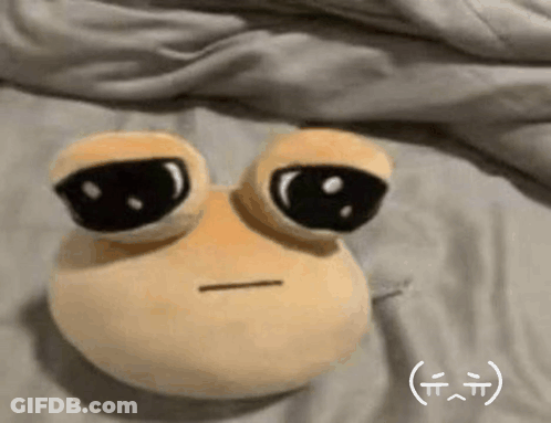 A Stuffed Animal With Big Eyes Is Laying On A Bed With A Smiley Face On It . GIF