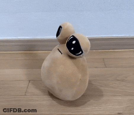 A Stuffed Animal With Big Eyes Is Sitting On A Hardwood Floor GIF