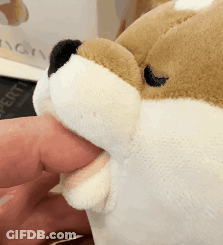 A Stuffed Animal With Its Mouth Open Is Being Held By A Hand GIF