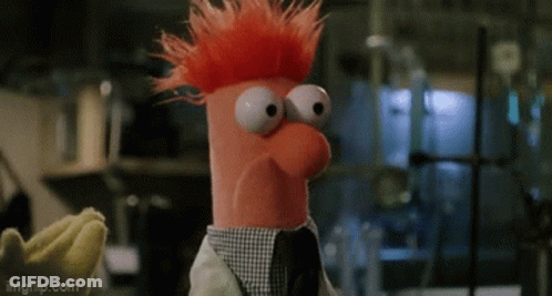 A Stuffed Animal With Red Hair And Big Eyes Is Wearing A Lab Coat And A Tie . GIF