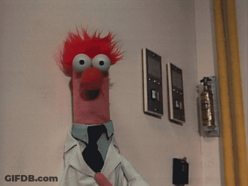 A Stuffed Animal With Red Hair Is Wearing A Lab Coat And A Tie GIF