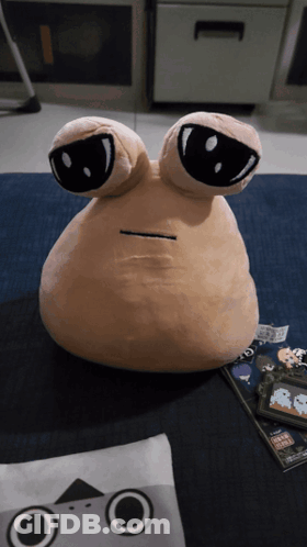 A Stuffed Animal With Two Eyes Is Sitting On A Carpet GIF