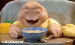 A Stuffed Baby Is Sitting In A High Chair Eating Cereal GIF