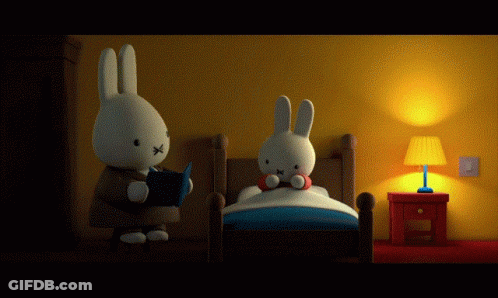 A Stuffed Bunny Is Reading A Book To Another Stuffed Bunny In Bed GIF