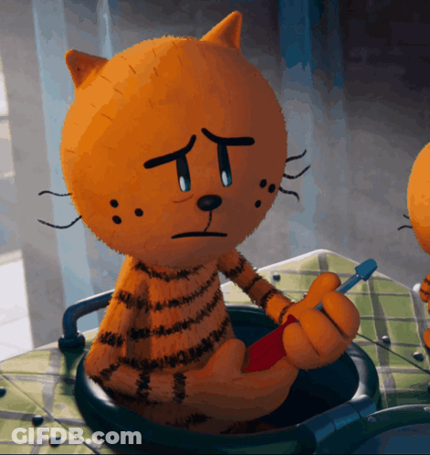 A Stuffed Cat With A Sad Face Is Holding A Red Object GIF
