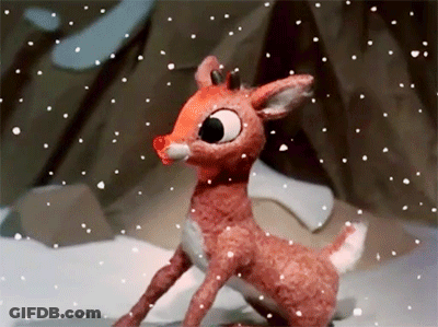 A Stuffed Deer With A Red Nose Is Standing In The Snow GIF