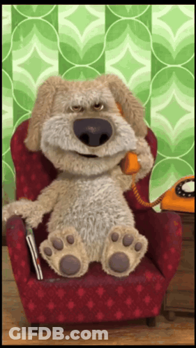 A Stuffed Dog Is Sitting In A Red Chair Talking On A Phone GIF