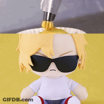 A Stuffed Doll Wearing Sunglasses Is Sitting On A Yellow Table GIF
