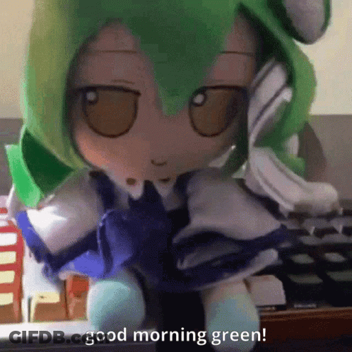 A Stuffed Doll With Green Hair Is Sitting In Front Of A Keyboard And Says " Good Morning Green " GIF
