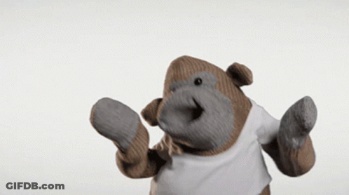 A Stuffed Gorilla Wearing A White T-Shirt And Mittens GIF