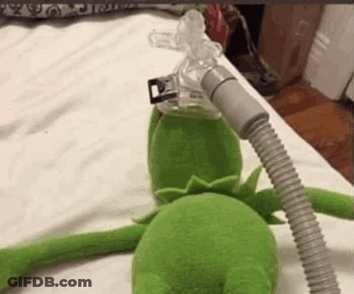 A Stuffed Kermit The Frog Is Laying On A Bed With An Oxygen Mask On . GIF