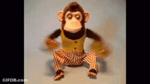 A Stuffed Monkey In Striped Pants Is Sitting On A Blue Surface . GIF