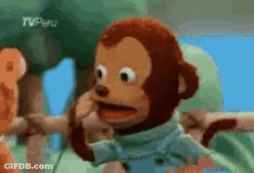 A Stuffed Monkey Is Making A Funny Face While Standing Next To Another Stuffed Animal . GIF