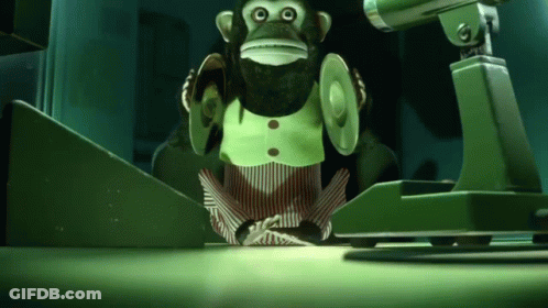 A Stuffed Monkey Is Sitting In Front Of A Camera In A Dark Room GIF
