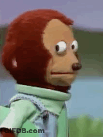 A Stuffed Monkey Wearing A Green Shirt And Tie Is Looking At The Camera . GIF