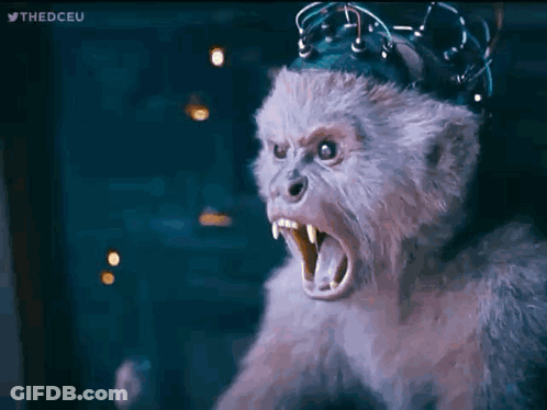 A Stuffed Monkey With A Crown On Its Head Is Looking At The Camera With Its Mouth Open . GIF