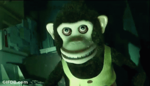 A Stuffed Monkey With Big Eyes And A Yellow Vest Is Standing In A Kitchen GIF