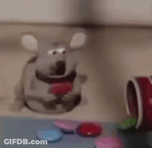 A Stuffed Mouse With A Heart In Its Mouth Is Sitting On A Table With Candy . GIF