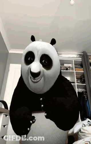 A Stuffed Panda Bear Is Sitting On A Bed In A Room GIF