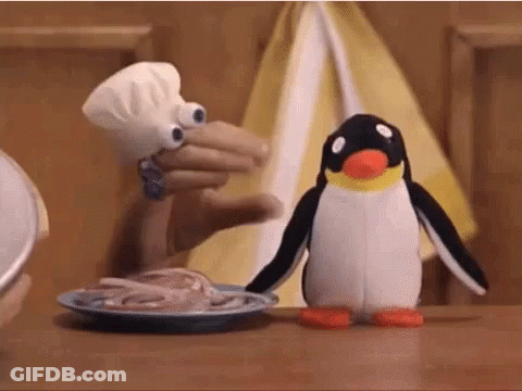 A Stuffed Penguin Is Standing Next To A Plate Of Squid . GIF