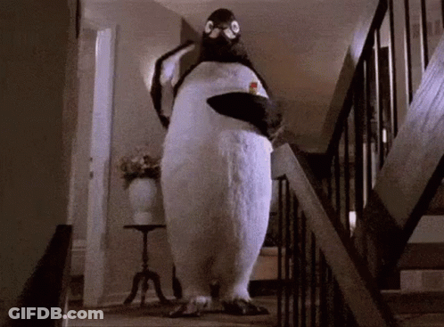 A Stuffed Penguin Is Walking Down A Set Of Stairs In A House . GIF