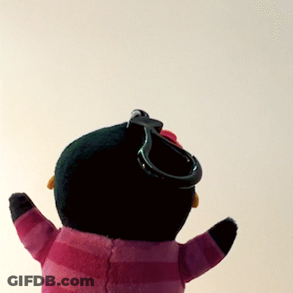 A Stuffed Penguin Wearing A Pink And Black Striped Sweater With A Keychain Attached To It GIF