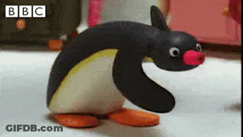 A Stuffed Penguin With A Pink Nose Is Standing On A White Surface . GIF