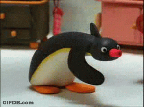 A Stuffed Penguin With A Red Nose Is Walking On A White Floor GIF