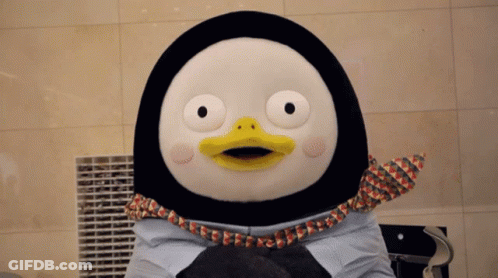 A Stuffed Penguin With A Yellow Beak Is Holding A Cat GIF