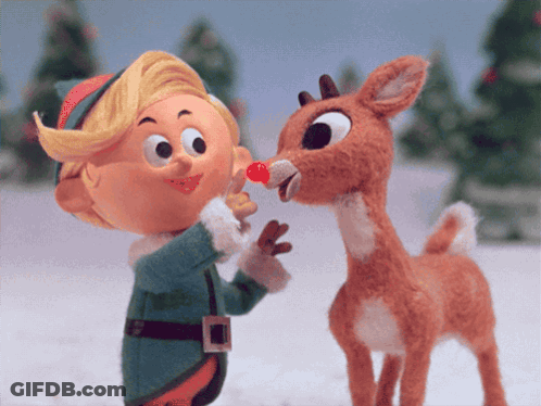 A Stuffed Reindeer With A Red Nose Is Being Kissed By A Little Elf GIF