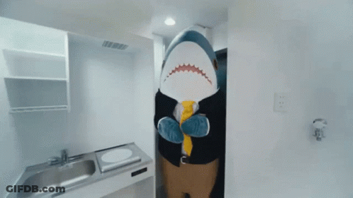 A Stuffed Shark Is Standing In A Kitchen Wearing A Suit And Tie GIF